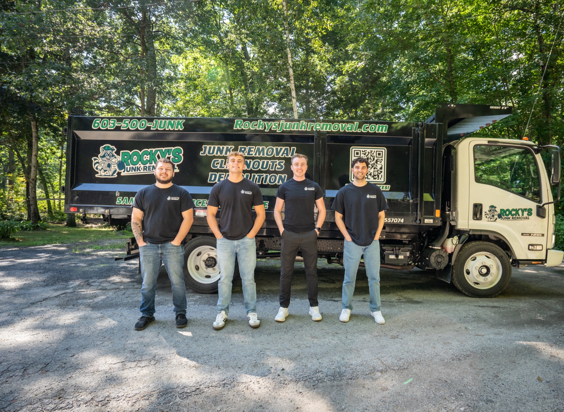 The Rocky's Junk Removal crew of four standing in front of their black dump truck