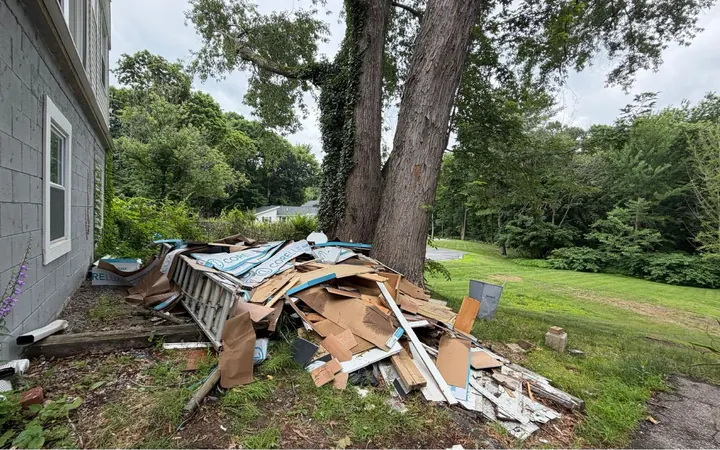Pile of cardboard, wood and building debris beside a house before pickup