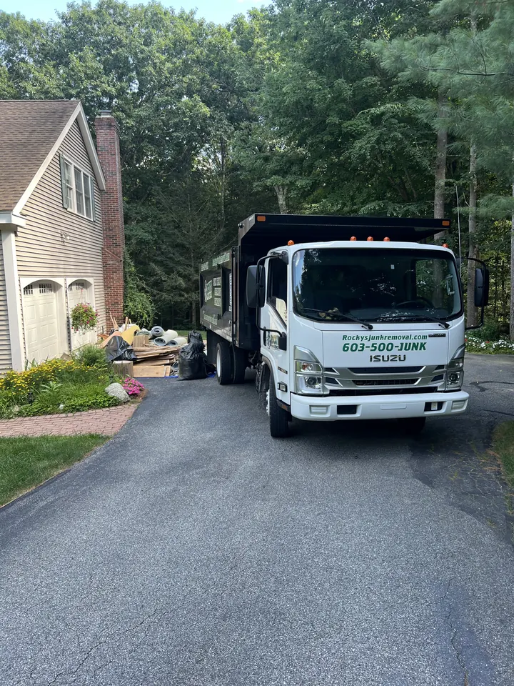 Rocky's Junk Removal dump truck seen from above, parked in a Bedford, NH driveway next to a home