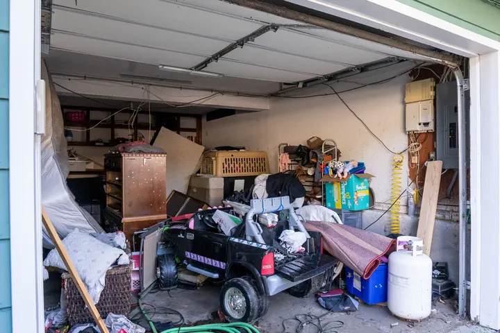 Derry, NH garage packed with furniture, bins, tools, and household items before Rocky's cleanout