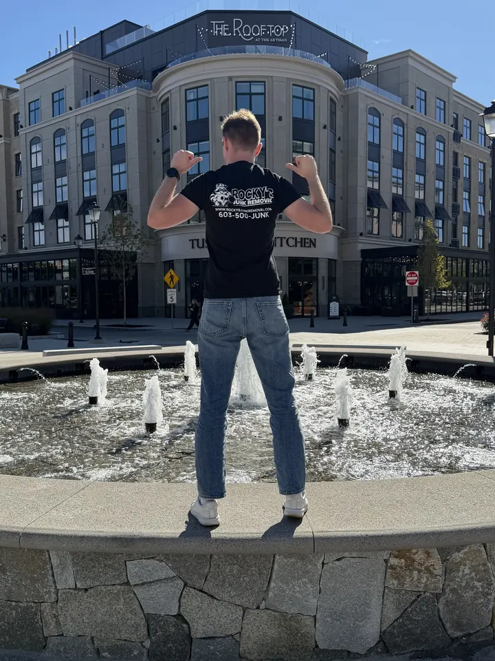 Rocky's Junk Removal crew member in a Rocky's shirt at the fountain at Tuscan Village in Salem, NH